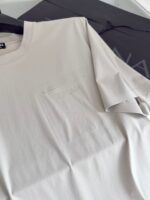 T-shirt minimalista chiara con tasca embossata HERON, stile semplice e versatile per ogni look.