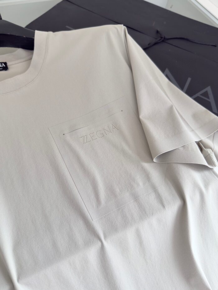 T-shirt minimalista chiara con tasca embossata HERON, stile semplice e versatile per ogni look.