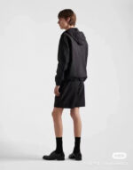 Look moderno minimalista uomo con giacca con cappuccio, bermuda eleganti e stile urbano sofisticato.