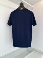 Maglietta navy minimalista su appendiabiti in tessuto leggero e elegante.