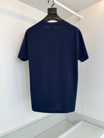 Maglietta navy minimalista su appendiabiti in tessuto leggero e elegante.