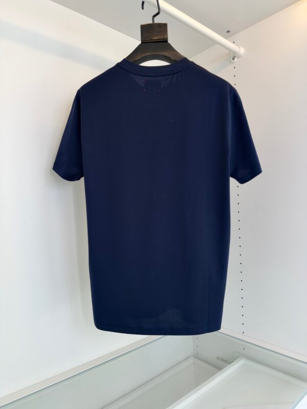 Maglietta navy minimalista su appendiabiti in tessuto leggero e elegante.
