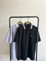 Polo shirt uomo in lavanda e nero su stand moderno, stile minimalista ed elegante.