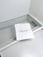 Maglietta bianca “COLD STORAGE” nel freezer, scena minimalista e ironica.