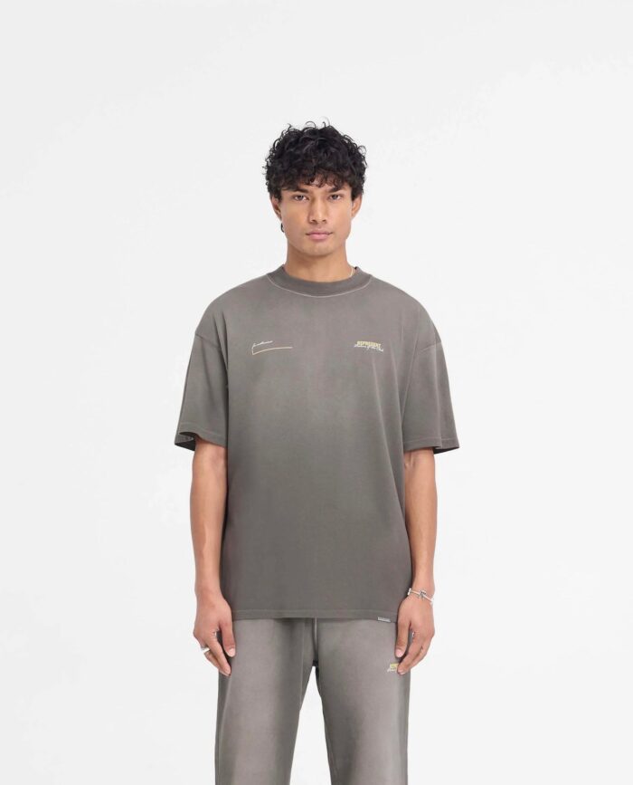 Uomo in streetwear minimalista con t-shirt e pantaloni neutri su sfondo bianco.