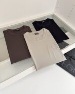 Magliette neutre piegate su vetro in ambiente retail elegante e minimalista