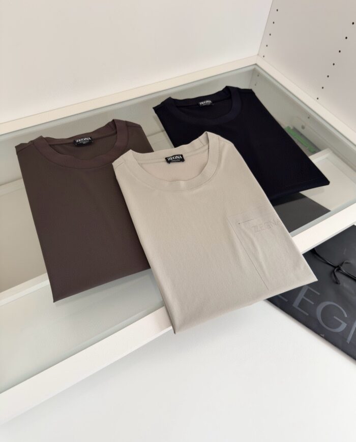 Magliette neutre piegate su vetro in ambiente retail elegante e minimalista