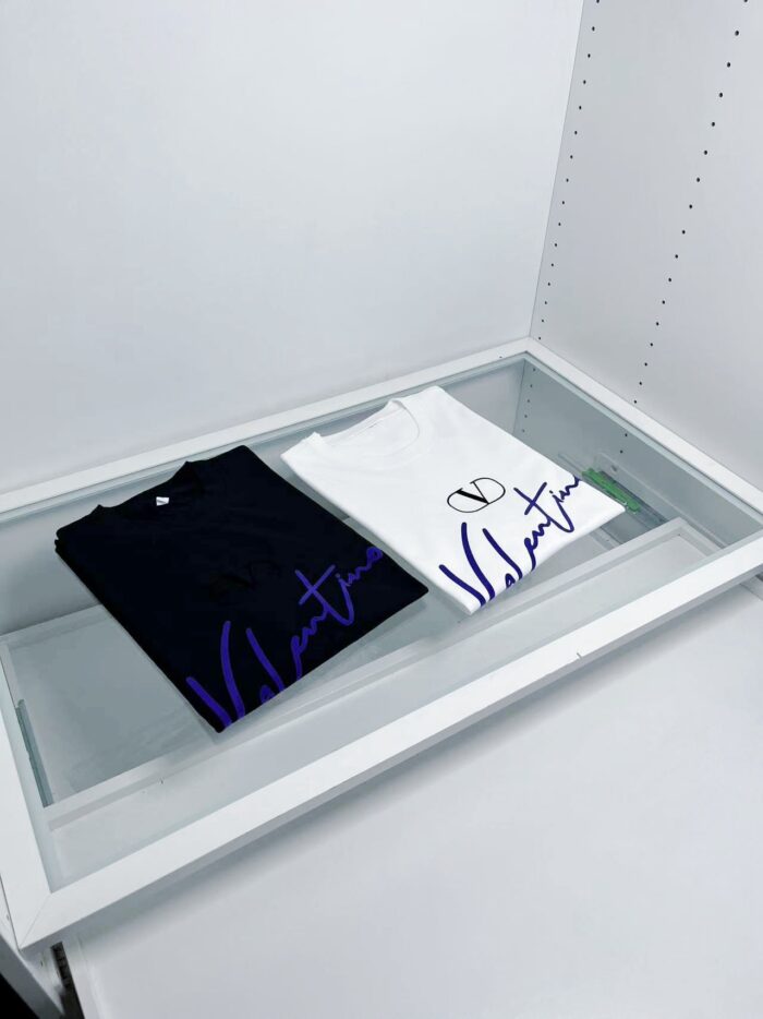 Esposizione di T-shirt di lusso in vetro minimalista, design elegante e contrasto bianco e nero.