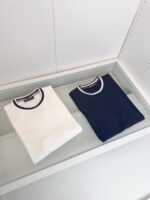 T-shirt bianca e navy minimalista su vetrina moderna, stile semplice e elegante.