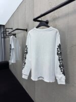 Camicia bianca con eleganti ricami floreali sulle maniche, stile moderno e minimalista.