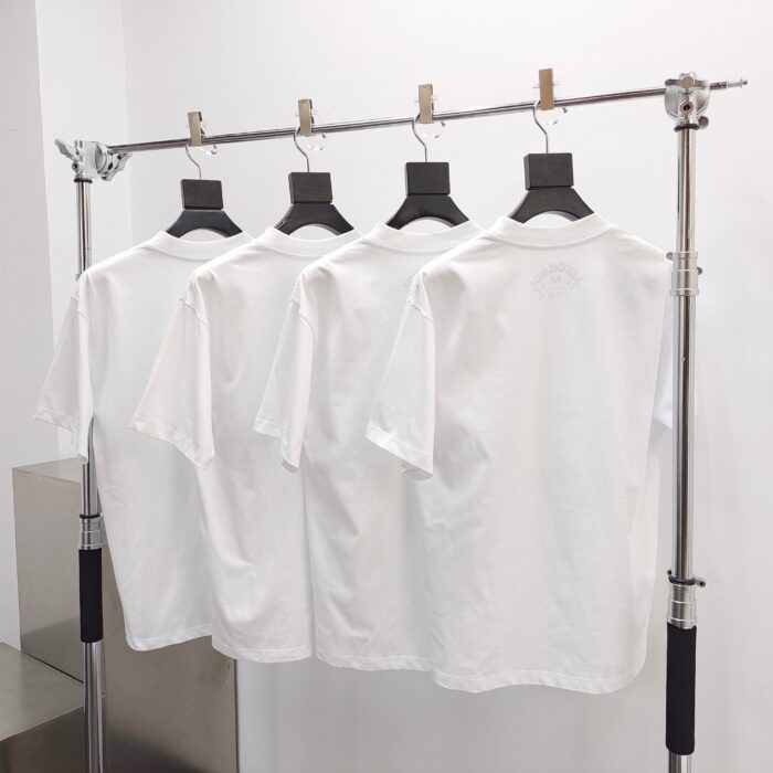 Esposizione elegante di quattro magliette bianche su rack moderno in negozio minimalista.