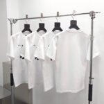 Esposizione minimalista di magliette bianche su supporto moderno in ambiente retail elegante.