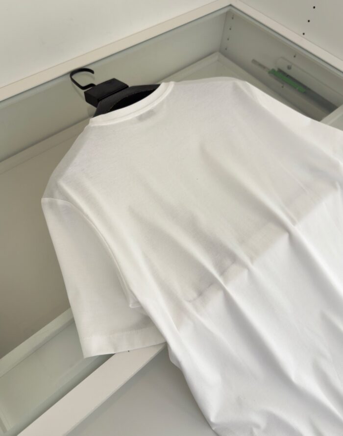 Maglietta bianca minimalista su appendiabiti nero, stile moderno e versatile per ogni occasione.