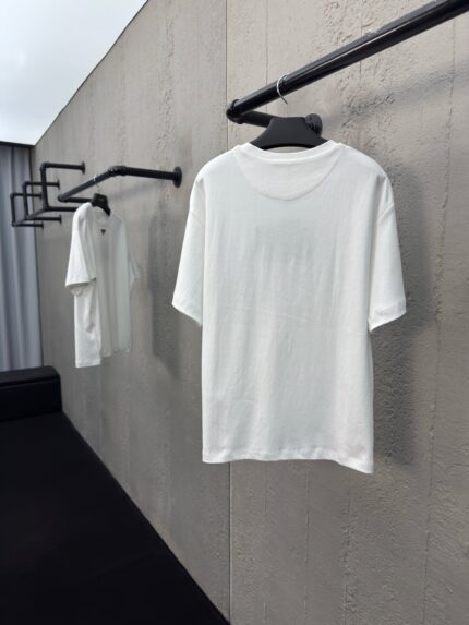 Magliette bianche minimaliste su supporto nero in boutique moderna, stile semplice ed elegante.