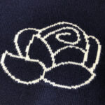 Rose minimalista ricamata su maglione scuro in tessuto a maglia, elegante e semplice.