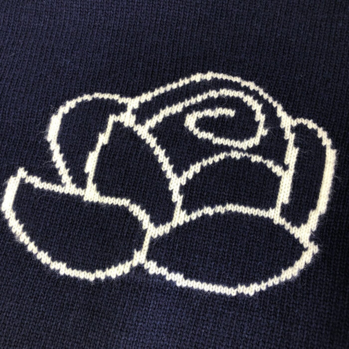 Rose minimalista ricamata su maglione scuro in tessuto a maglia, elegante e semplice.