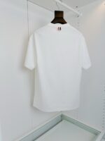 Maglietta bianca minimalista su appendiabiti di legno, stile semplice ed elegante per look casual.