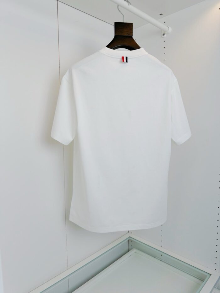 Maglietta bianca minimalista su appendiabiti di legno, stile semplice ed elegante per look casual.