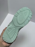 Suola di sneaker verde menta con logo CD, design ergonomico e trame antiscivolo elegante.