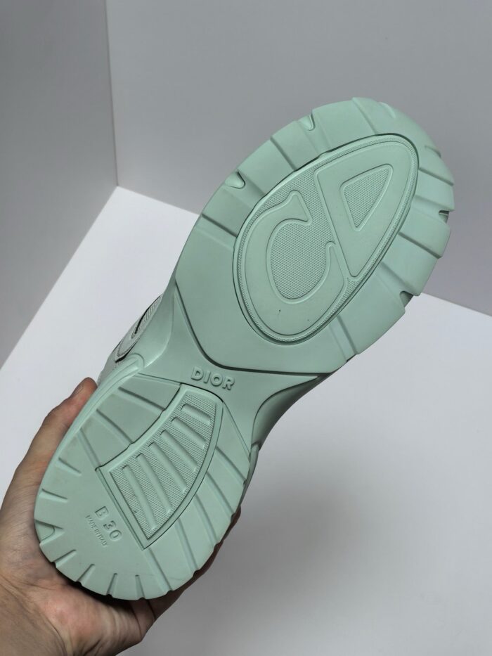 Suola di sneaker verde menta con logo CD, design ergonomico e trame antiscivolo elegante.