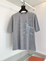 T-shirt grigia casual con stampa astratta blu e bianco, stile moderno e comfort quotidiano.