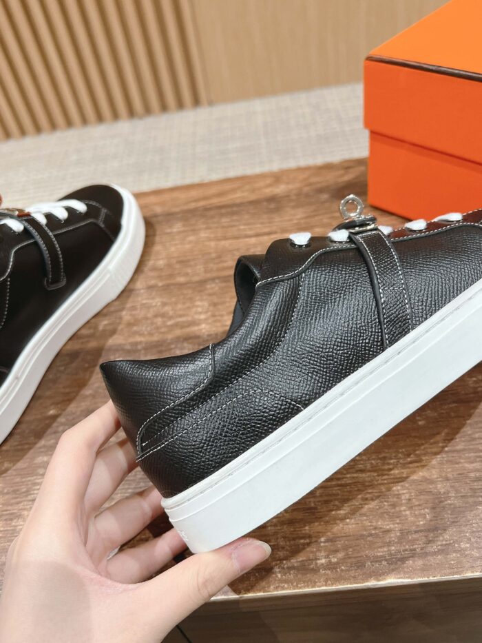 Sneaker nere moderne con lacci bianchi su superficie di legno, in esposizione elegante e di tendenza.