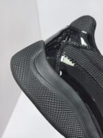 Sneaker nera moderna con tomaia in mesh, dettagli lucidi e suola in gomma ad alta grip.