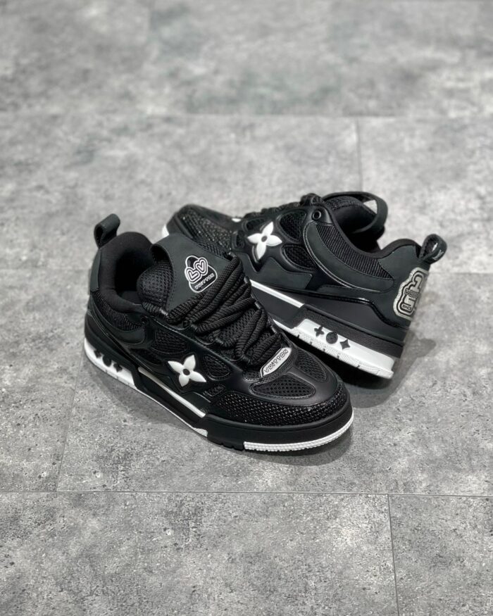 Scarpe nere moderne in pelle e mesh con dettagli bianchi e logo stilizzato, stile urbano e versatile.
