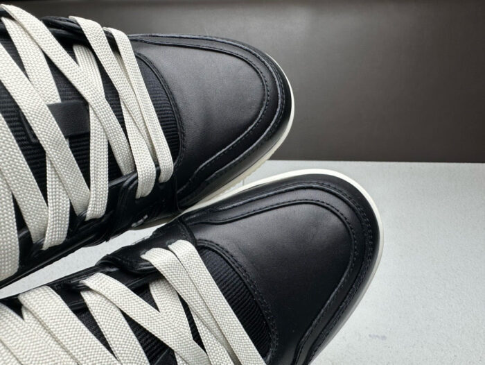 Sneakers nere in pelle lucida con lacci chiari e design moderno, eleganti e di tendenza.