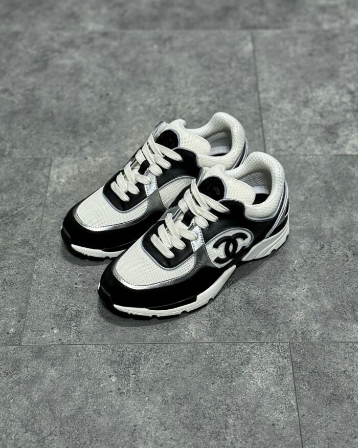 Sneaker moderne nero e bianco, stile urbano, suola antiscivolo e logo elegante.