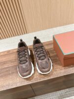 Sneakers marroni moderni su superficie di legno con scatola arancione e dettagli eleganti.