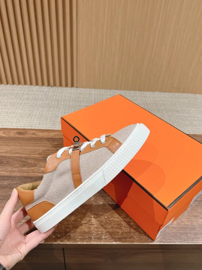 Sneaker casual moderna con tomaia beige e dettagli in pelle, accompagnata da scatola arancione vivace.