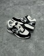 Sneakers di lusso nero e bianco con logo prominente, stile moderno e dettagli raffinati.