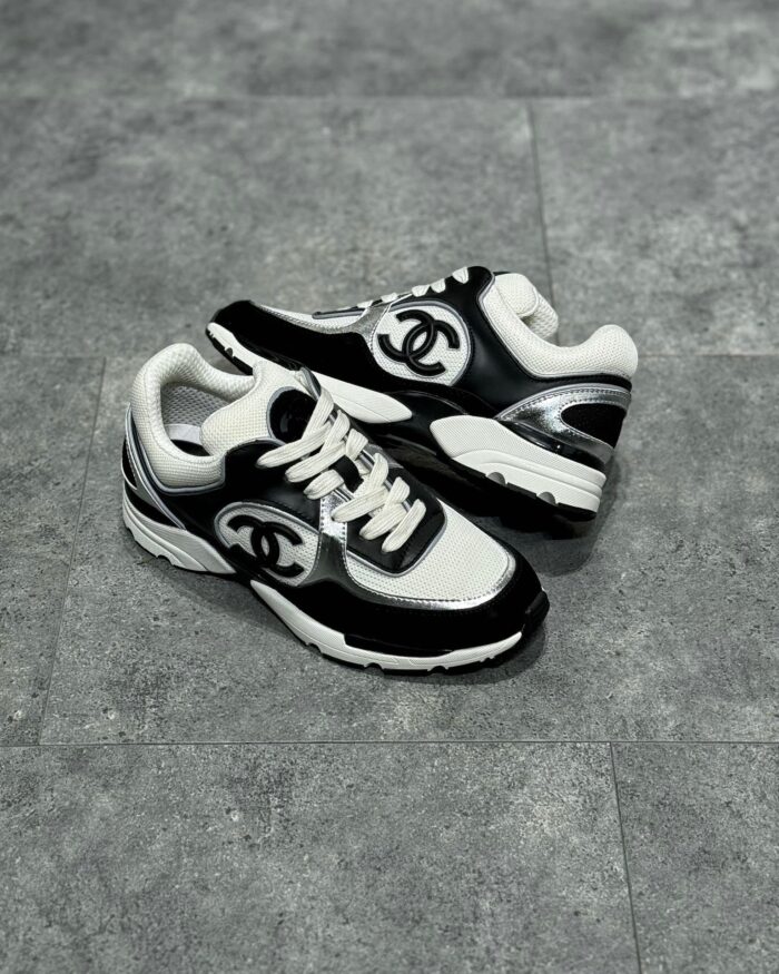 Sneakers di lusso nero e bianco con logo prominente, stile moderno e dettagli raffinati.