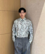 Uomo moderno con camicia floreale e pantaloni eleganti in stile minimalista.