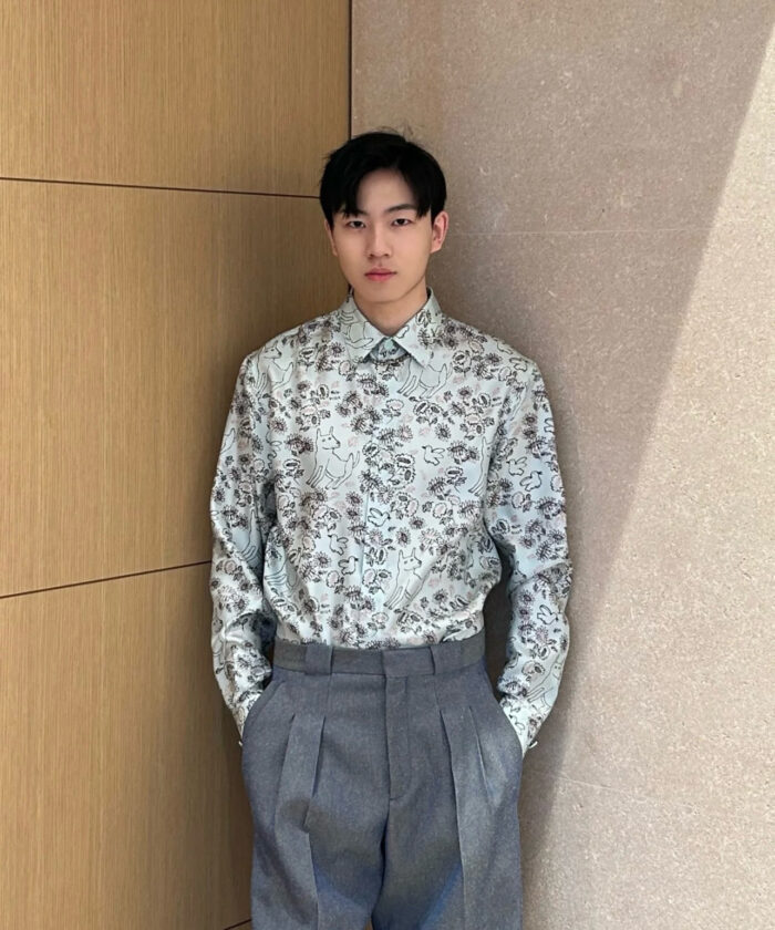 Uomo moderno con camicia floreale e pantaloni eleganti in stile minimalista.