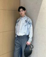 Uomo stile moderno con camicia colorata, pantaloni oversize e borsa elegante.