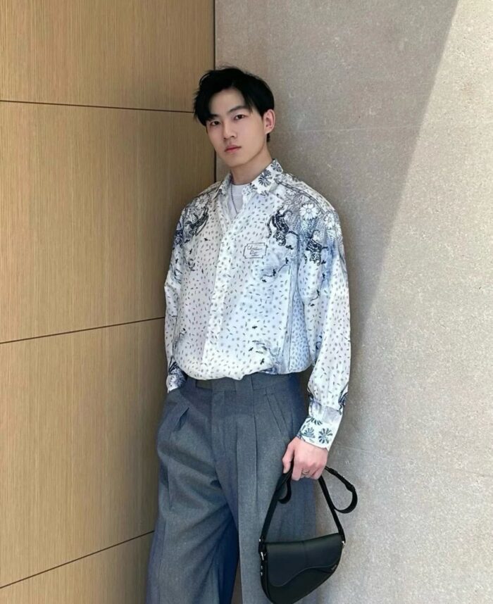 Uomo stile moderno con camicia colorata, pantaloni oversize e borsa elegante.