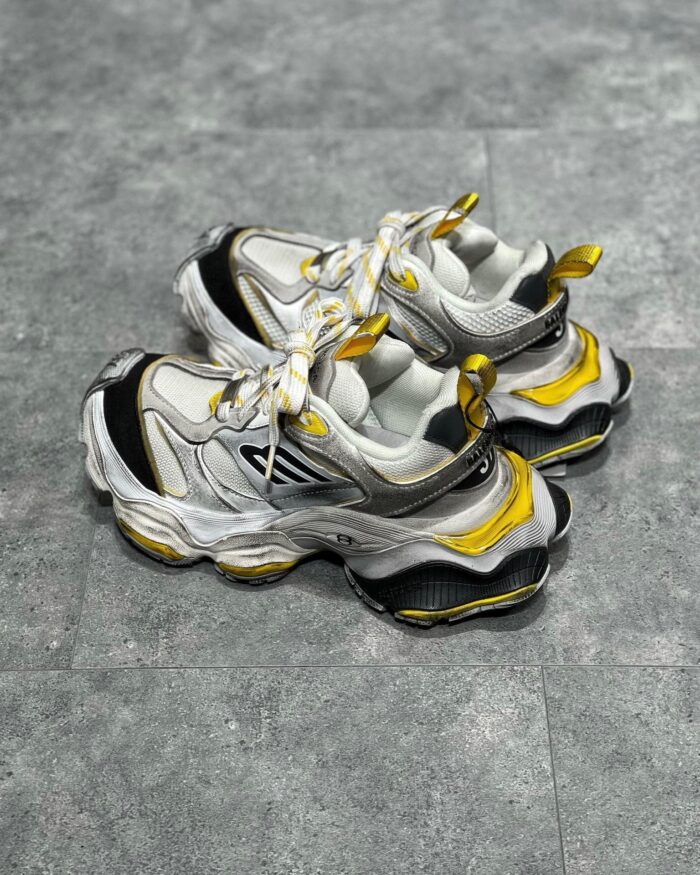 Scarpe sportive futuristiche bianche, grigie e gialle con suola spessa e design innovativo.