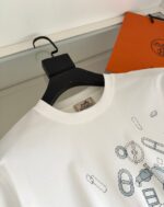 Maglietta bianca moderna con grafica geometrica, presentata su un appendino nel contesto di moda elegante.