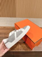 Sneaker moderna grigia e bianca con scatola arancione, stile casual e versatile.