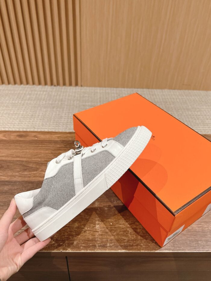 Sneaker moderna grigia e bianca con scatola arancione, stile casual e versatile.