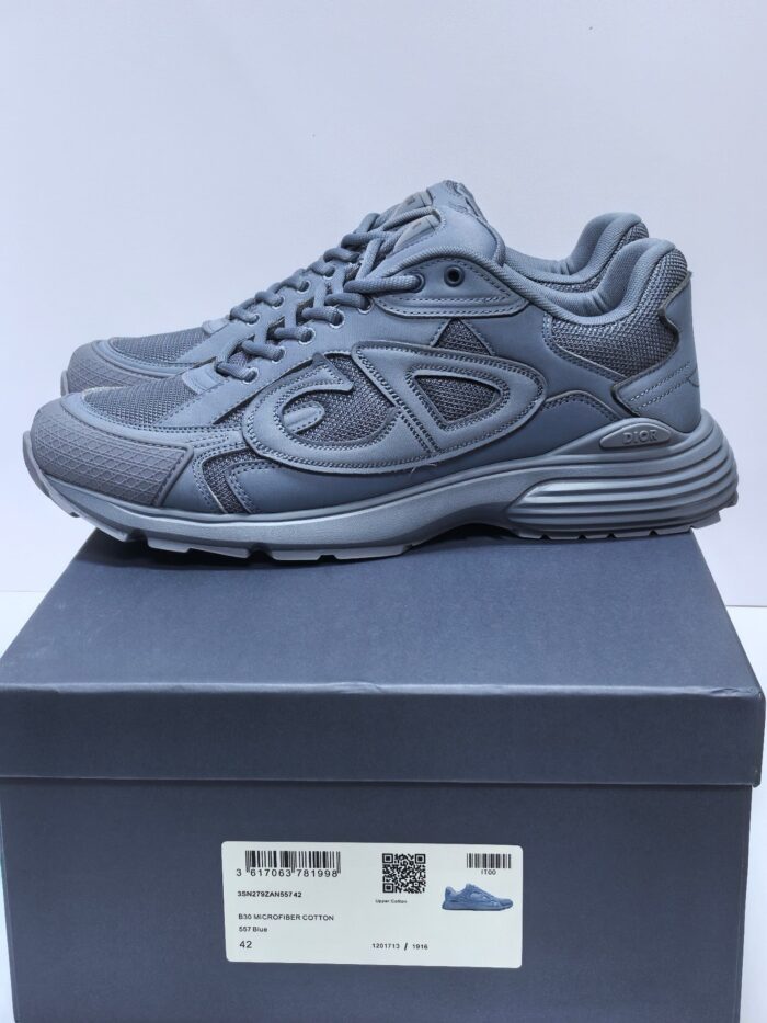 Scarpe sportive moderne grigie con suola antiscivolo e logo sulla linguetta, su scatola minimalista.