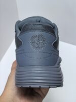 Sneaker grigia moderna con logo circolare, design minimale e suola antiscivolo comfort; vista posteriore.