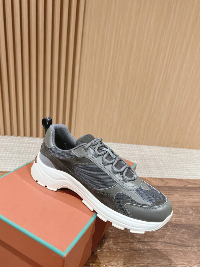 Sneaker grigia moderna con suola bianca, stile casual eleganza su scatola in ambiente raffinato.