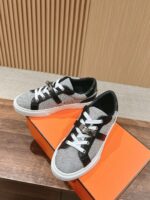 Scarpe sportive grigie moderne con lacci bianchi su scatola arancione, su superficie in legno.