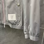 Giacca grigia moderna con bottoni a pressione, elastico ai polsini e design minimale.
