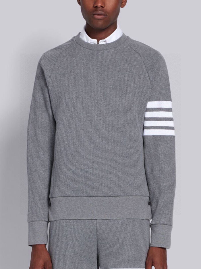 Felpa grigia moderna con dettagli a righe e layering classico, stile athleisure contemporaneo.