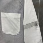 Dettagli minimalisti di una maglietta grigia con tasca e bordo sul polsino.