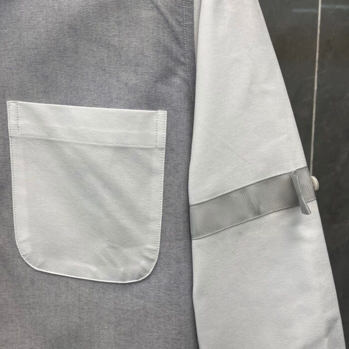 Dettagli minimalisti di una maglietta grigia con tasca e bordo sul polsino.